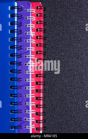 Several multi-colored notebooks on a spiral on a black background Stock Photo