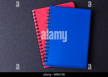 Several multi-colored notebooks on a spiral on a black background Stock Photo