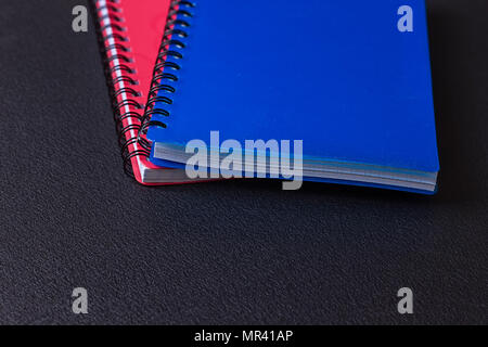 Several multi-colored notebooks on a spiral on a black background Stock Photo