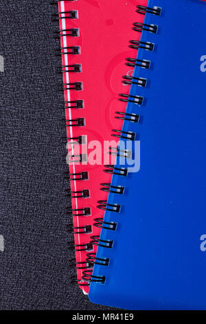 Several multi-colored notebooks on a spiral on a black background Stock Photo