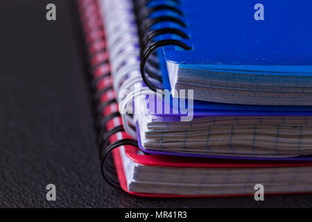 Several multi-colored notebooks on a spiral on a black background Stock Photo