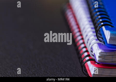 Several multi-colored notebooks on a spiral on a black background Stock Photo