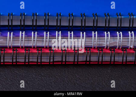 Several multi-colored notebooks on a spiral on a black background Stock Photo