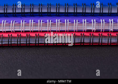 Several multi-colored notebooks on a spiral on a black background Stock Photo