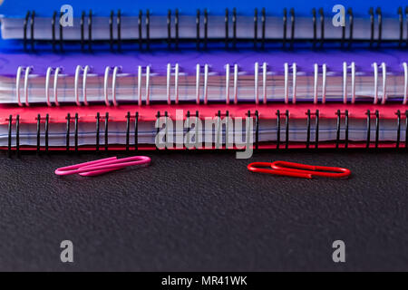 Several multi-colored notebooks on a spiral on a black background Stock Photo