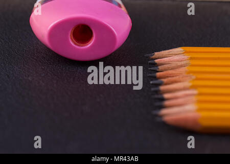 Simple pencils and a pink pencil sharpener on a black background Stock Photo