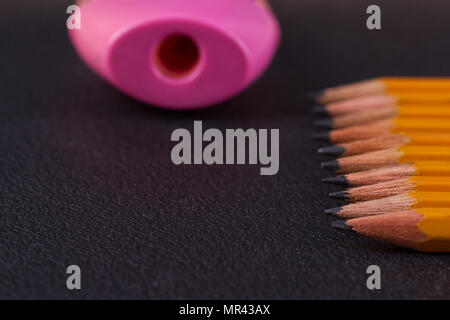 Simple pencils and a pink pencil sharpener on a black background Stock Photo