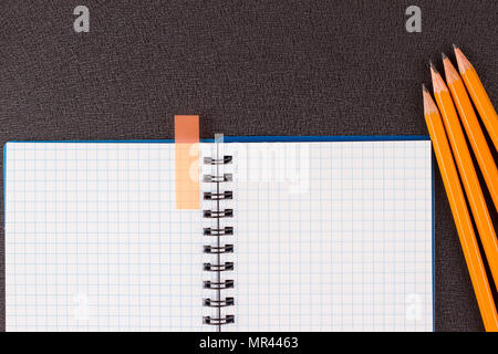 Top view of office supplies of dark table. Opened notepad and colorful pencils on black background Stock Photo