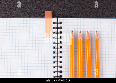 Top view of office supplies of dark table. Opened notepad and colorful pencils on black background Stock Photo
