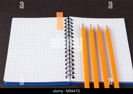 Top view of office supplies of dark table. Opened notepad and colorful pencils on black background Stock Photo