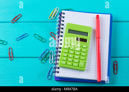 Calculator and pencil on notepad on the blue background Stock Photo