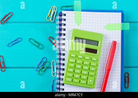 Calculator and pencil on notepad on the blue background Stock Photo