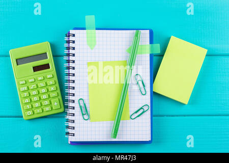 green calculator with a paper sticker on a blue background, top view Stock Photo