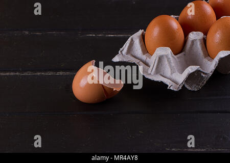 Cardboard egg box And eggshell shells on black wooden background. Eggs container Stock Photo