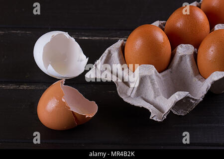 Cardboard egg box And eggshell shells on black wooden background. Eggs container Stock Photo