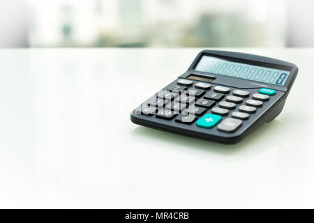 Calculator on the white table near window, sideview isolated Stock Photo