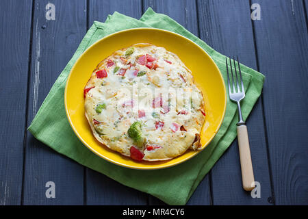Hearty and tasty breakfast, traditional in the hotel, omelette from chicken eggs with cheese, fresh vegetables - cucumber and tomato on the black wood Stock Photo