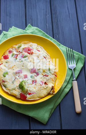 Hearty and tasty breakfast, traditional in the hotel, omelette from chicken eggs with cheese, fresh vegetables - cucumber and tomato on the black wood Stock Photo