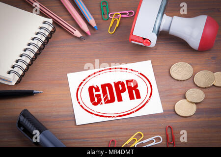 GDPR General Data Protection Regulation stamp. Wooden office desk with stationery, money and a note pad Stock Photo