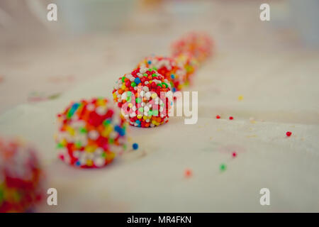 Close up on white chocolate balls covered with candies arranged in a row. Narrow focus. Stock Photo