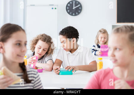 African-american boy eating lunch with friend in the school's canteen Stock Photo