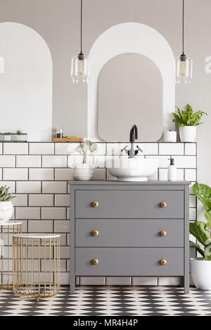 Lamps above grey cabinet with washbasin in modern bathroom interior with mirror. Real photo Stock Photo