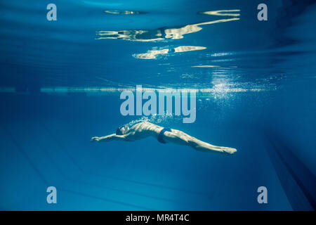 underwater picture of young swimmer in goggles exercising in swimming pool Stock Photo