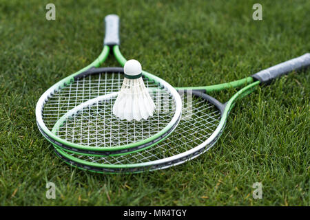 Close up of shuttlecock on badminton rackets lying on green grass Stock Photo