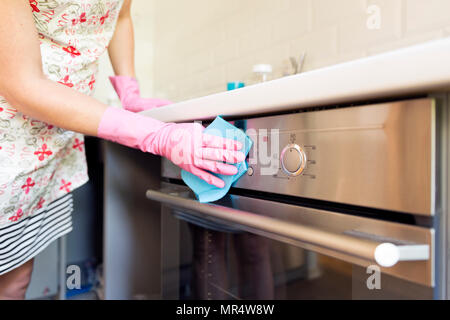 Woman's hand with pink protective gloves cleaning oven door. People, housework, cleaning concept Stock Photo