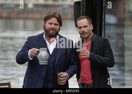 Actors Antoine Monot, Jr. (left) and Wanja Mues (right) pose on the terrace of the houseboat that is owned by Mues' character Leo in the TV show with two glasses of cider and a Bembel (a local type of stoneware jug, used for cider). 4 new episodes of the relaunch of the long running TV series 'Ein Fall fuer zwei’ (A case for two) are being filmed in Frankfurt for the German state TV broadcaster ZDF (Zweites Deutsches Fernsehen). It stars Antoine Monot, Jr. as defence attorney Benjamin ‘Benni’ Hornberg and Wanja Mues as private investigator Leo Oswald. The episodes are directed by Thomas Nennst Stock Photo