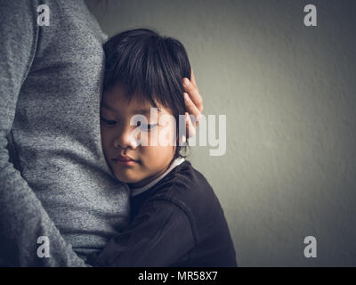 Sad little boy being hugged by his mother at home. Parenthood, Love and togetherness concept. Stock Photo