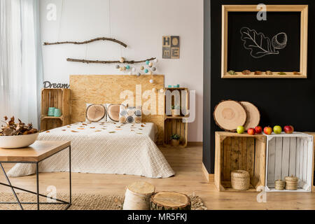 Light bedroom with black and white wall, double bed and DIY wooden furniture Stock Photo
