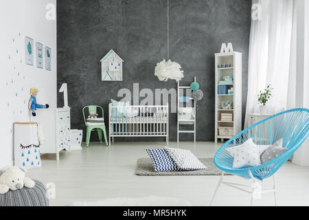 Nursery room in scandinavian style with cot, chair and pouf Stock Photo