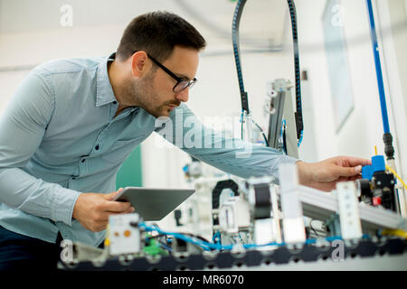 Portrait of handsome young man in the electronic workshop using digital tablet Stock Photo