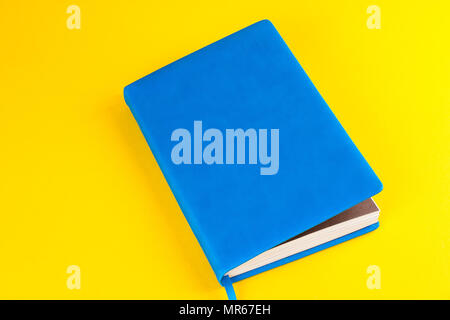 Blue closed diary on a yellow background Stock Photo