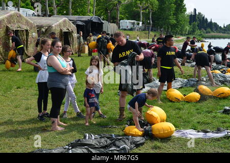 A U.S. Army Paratrooper assigned to 1st Battalion, 503rd Infantry Regiment, 173rd Airborne Brigade, packs his wet parachute with his family after a water jump into Lake Garda near Pacengo, Italy, May 18, 2017. The 173rd Airborne Brigade is the U.S. Army Contingency Response Force in Europe, capable of projecting ready forces anywhere in the U.S. European, Africa or Central Commands' areas of responsibility within 18 hours. (U.S. Army Photo by Visual Information Specialist Paolo Bovo/Released) Stock Photo