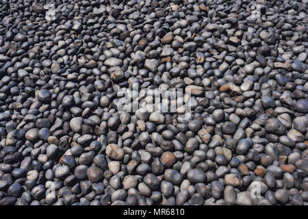 Clsoeup of cobble stones on Cobble Beach in Newport, Oregon.  The dark stones formed from lava being eroded over millions of years by the sea. Stock Photo