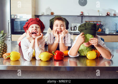 Funny children in the uniform of cooks in the kitchen. Stock Photo