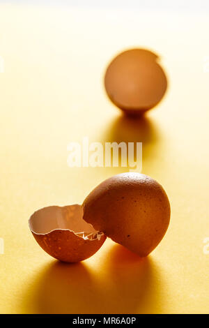 Egg shells on yellow surface with more shells in the background. View in the foreground. Food for a healthy life. Vertical image. Stock Photo
