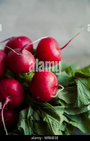 Close up image of heap of fresh radishes with tops and leaves on wooden rustic background Stock Photo