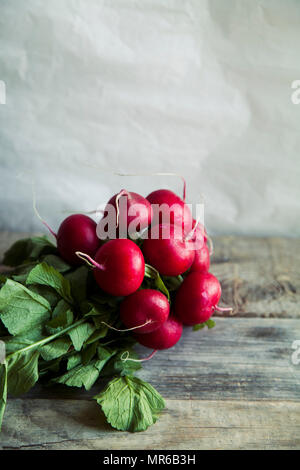 Heap of fresh radishes with tops and leaves on wooden rustic background Stock Photo