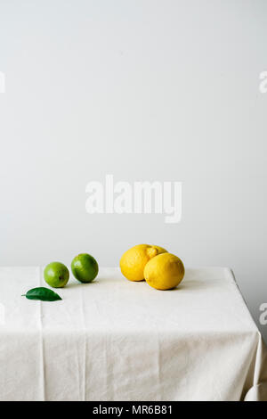 Minimalistic composition with citrus fruits on a table covered with white linen tablecloth Stock Photo