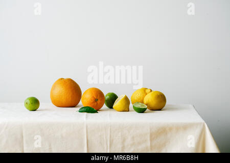 Minimalistic composition with citrus fruits on a table covered with white linen tablecloth Stock Photo