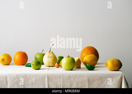 Citrus fruits, pear and apples on a table covered with linen tablecloth Stock Photo