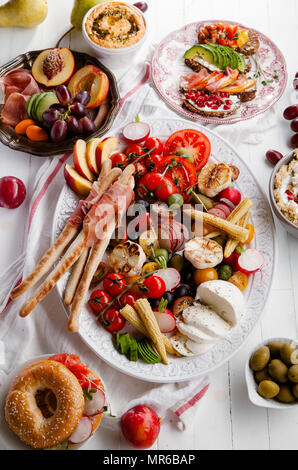 Variety of snacks prepared for picnic wine summer party with fresh fruits, vegetables, prosciutto and chesse Stock Photo