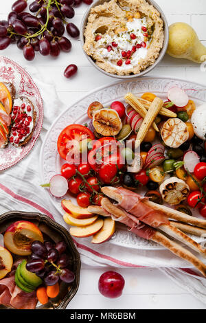 Variety of snacks prepared for picnic wine summer party with fresh fruits, vegetables, prosciutto and chesse Stock Photo
