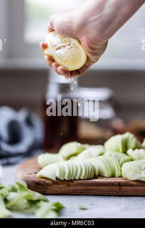 Squeezing lemon juice over freshly peeled apples Stock Photo