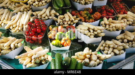 Market stall with fresh spring season vegetables at Parisian street farmers market. White asparagus, tomatoes, cucumbers. Stock Photo