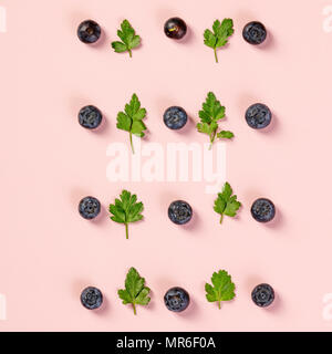 Pattern of blueberry and parsley leaves on light pink background. Flat lay, top view. Food background. Stock Photo