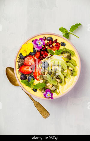 Mango banana pineapple turmeric breakfast superfoods smoothie bowl topped with fruits, berries and seeds. Overhead top view flat lay Stock Photo